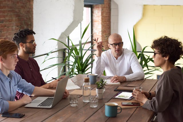 five coworkers holding a meeting around a conference table