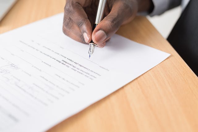 person signing a lease agreement with a silver pen