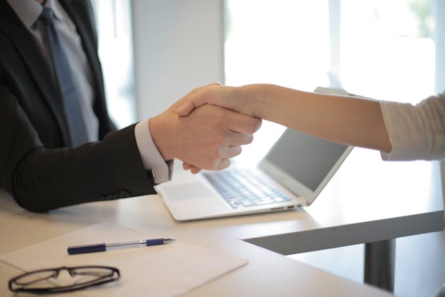two people shaking hands across a desk