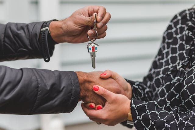 people shaking hands while exchanging house keys