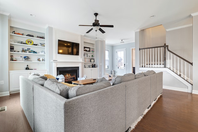 living room with L-shaped grey couch and tv over the fireplace