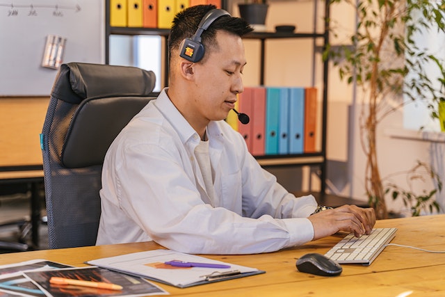 person working on their laptop at their desk while wearing a phone headset