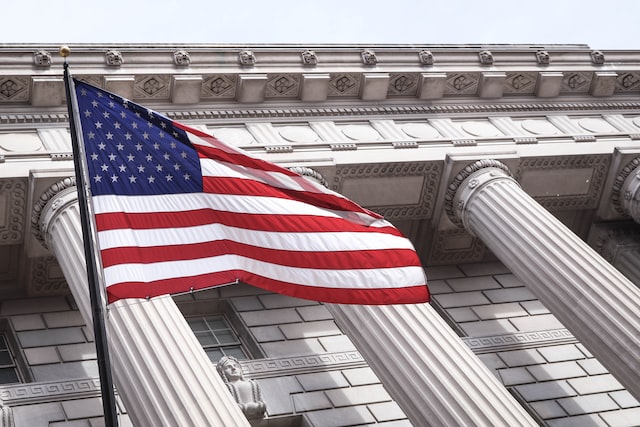 an American flag outside a building with white columns